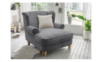 Loveseat-Sessel in der Farbe Grau mit einem beigefarbenen Kissen, in einem Raum stehend