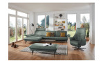 Komfort-Ecksofa 1928 in der Farbausführung grün mit Dekokissen, einem Hocker und einem Sessel im Raum stehend mit der Sitztiefenverstellung in linken Element