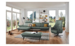 Komfort-Ecksofa 1928 in der Farbausführung grün mit Dekokissen, einem Hocker und einem Sessel im Raum stehend