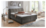 Boxspringbett Ole in Taupe aus einem Stoffbezug. Auf einem dekorierten Hintergrund.