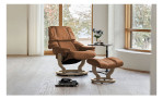 Stressless Sessel Reno mit braunem Lederbezug und eichefarbenen Gestell mit dazu passendem Hocker