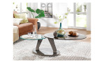 Couchtisch MONDO Varium mit einer Glas-Keramik Tischplatte in Zementgrau und einer transparenten Glastischplatte mit einem Stahlgestell in Taupe. Auf einem dekorierten Hintergrund.
