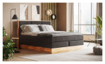 Boxspringbett VALMONDO Incana in einem Stoffbezug in Charcoal und einem Sichtholzrahmen in Eiche. Auf einem dekorierten Hintergrund