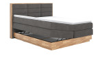 Boxspringbett VALMONDO Incana in einem Stoffbezug in Dark Grey und einem Sichtholzrahmen in Eiche. mit geöffneten Bettkasten