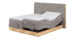 Boxspringbett VALMONDO Incana in einem Stoffbezug in Taupe und einem Sichtholzrahmen in Eiche. Mit gezeigter motorischen vesrtellung