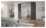 Komfort-Drehtürenschrank vito Dioso Mit einer Farbglasfront in Basalt und einem Korpus in Graphit aus Holzwerkstoff. Auf einem dekorierten Hintergrund